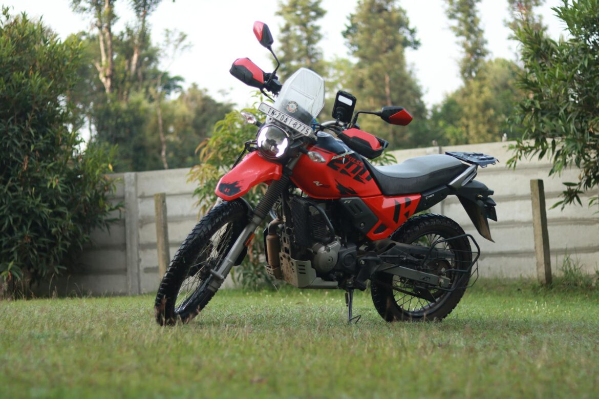 Moto rouge double sport garée sur une pelouse herbeuse à Madikeri, Karnataka, Inde.